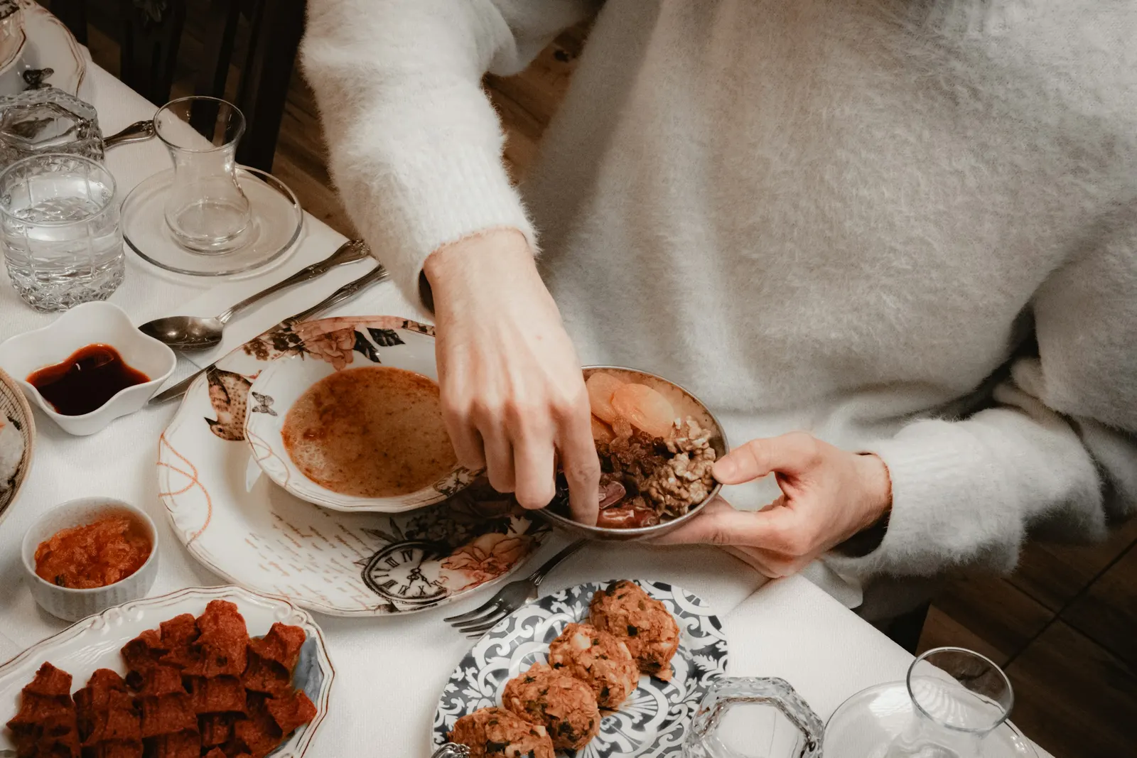 hands serving food onto a small plate at a shared table