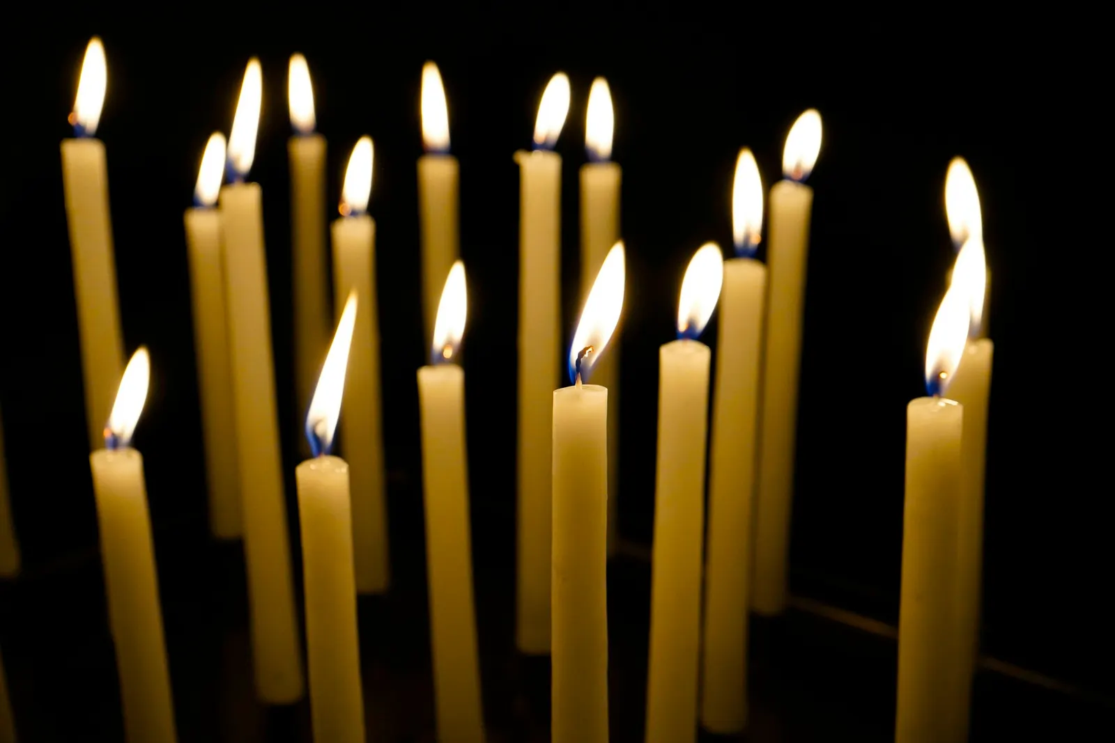 tall taper candles glowing in a dark room